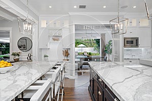 Marble kitchen with a white island, and chairs in a new construction home in Encino, California