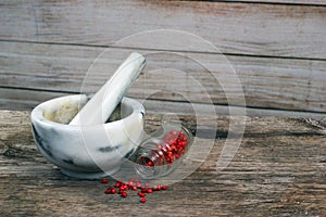 Marble mortar and pestle on old wooden table. Small glass jar wi