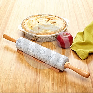 Marble rolling pin on bamboo surface with ingredients for apple pie.