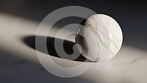Marble sphere with gray veining rests on a smooth surface casting a soft