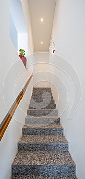 Marble stairs with wooden handrails and spotlights in the modern house