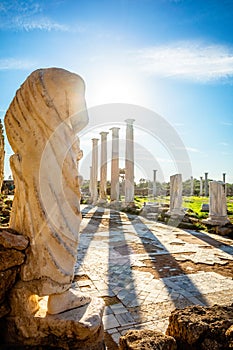 Marble statue under the sun rays and ancient columns at Salamis, Greek and Roman archaeological site, Famagusta, North Cyprus