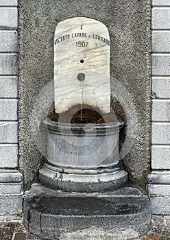 Marble and stone public fountain on the central square of Varenna, Italy.