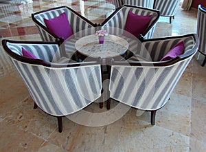 Marble table surrounded by upholstered armchairs with purple cushions