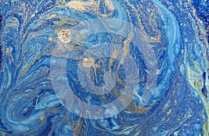 Marbled blue abstract background with golden sequins. Liquid marble ink pattern.