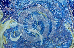 Marbled blue abstract background with golden sequins. Liquid marble ink pattern.