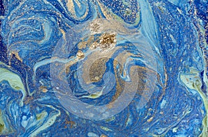 Marbled blue abstract background with golden sequins. Liquid marble ink pattern.