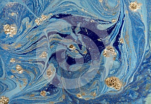 Marbled blue abstract background with golden sequins. Liquid marble ink pattern.