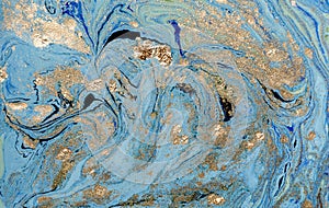 Marbled blue abstract background with golden sequins. Liquid marble ink pattern.