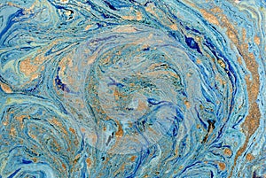 Marbled blue abstract background with golden sequins. Liquid marble ink pattern.