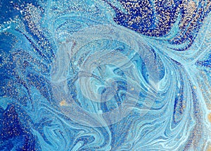 Marbled blue abstract background with golden sequins. Liquid marble ink pattern.