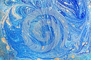 Marbled blue abstract background with golden sequins. Liquid marble ink pattern.