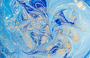 Marbled blue abstract background with golden sequins. Liquid marble ink pattern.