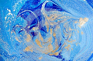 Marbled blue abstract background with golden sequins. Liquid marble ink pattern.