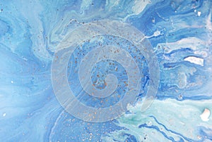 Marbled blue abstract background with golden sequins. Liquid marble ink pattern.