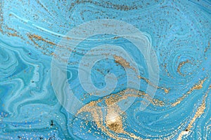 Marbled blue abstract background with golden sequins. Liquid marble ink pattern.