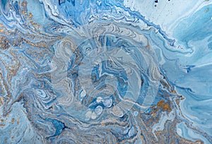 Marbled blue abstract background with golden sequins. Liquid marble ink pattern.