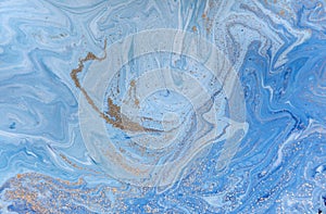 Marbled blue abstract background with golden sequins. Liquid marble ink pattern.