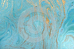 Marbled blue abstract background with golden sequins. Liquid marble ink pattern.