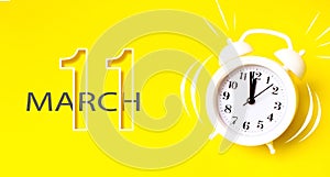 March 11st . Day 11 of month, Calendar date. White alarm clock with calendar day on yellow background. Minimalistic concept of