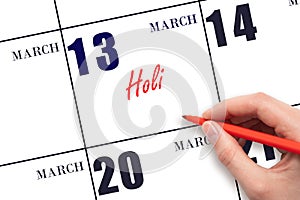 March 13. Hand writing text Holi on calendar date. Save the date.