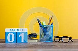 March 1st. Day 1 of march month, calendar on table with yellow background and office or school supplies. Spring time