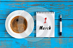 March 1st. Day 1 of month, calendar written and morning coffee cup at blue wooden background. Spring time, Top view