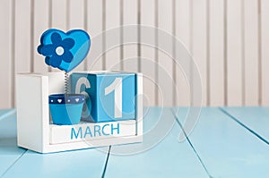 March 1st. Image of march 1 wooden color calendar with flower and heart on white background. First spring day, empty