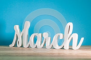 March - 1st month of spring. Wooden carved word at light blue background. Card for Mothers day, 8 March, Easter