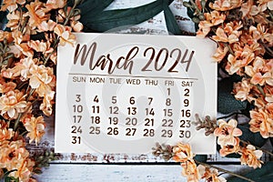 March 2024 monthly calendar with flower bouquet decoration on wooden background