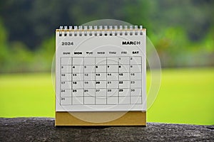 March 2024 white calendar with green blurred background.