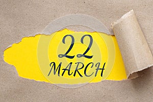march 22. 22th day of the month, calendar date. Hole in paper with edges torn off. Yellow background is visible through