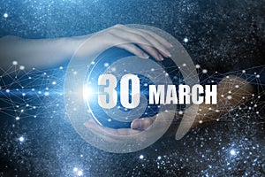 March 30th. Day 30 of month, Calendar date. Human holding in hands earth globe planet with calendar day. Elements of this image