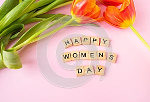 March 8, postcard. Happy Women\'s Day text sign with orange tulips on pink background.