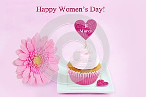 March 8 Women's Day pink greeting card with cupcake, heart and gerbera daisy.