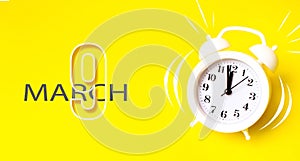 March 9th. Day 9 of month, Calendar date. White alarm clock with calendar day on yellow background. Minimalistic concept of time,