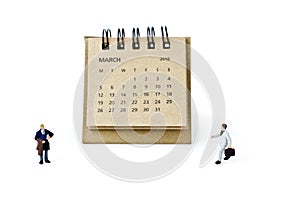 March. Calendar sheet and miniature plastic businessmen on white