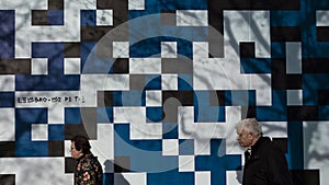 9 March 2020, A couple of seniors walking in the sideway with an abstract wall illustration background in Braga.