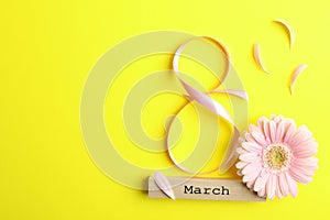 8 March, International Women`s Day. Figure eight of pink ribbon with beautiful gerbera on yellow background