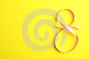 8 March, International Women`s Day. Figure eight of pink ribbon on yellow background