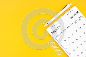 March 2024, Monthly desk calendar for 2024 year and pen with paper clips on yellow color background