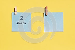 March 2st. Day of 2 month, calendar date. Two blue sheets for writing on a yellow background. Top view, copy space. Spring month, photo