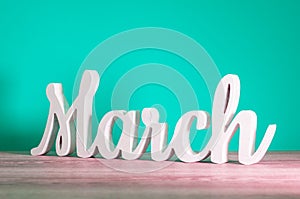 March - wooden carved letters. Beginning of march month, calendar on light turquoise background. Spring coming
