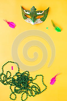 Mardi gras accessories flat lay on bright yellow background, top view, copy space. Frame with traditional Mardi gras beads, masks