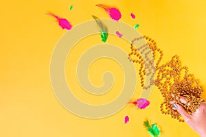 Mardi gras accessories flat lay on bright yellow background, top view, copy space. Frame with traditional Mardi gras beads, masks