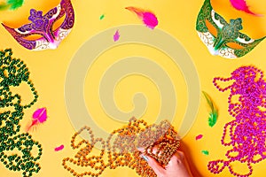 Mardi gras card flat lay on bright yellow background, top view, copy space. Frame with traditional Mardi gras beads, masks,