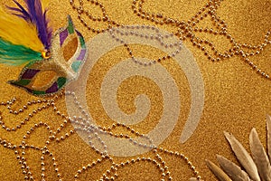 Mardi gras or carnival mask with beads on gold glowing background. Venetian mask.