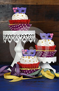 Mardi Gras cupcakes with purple mask toppers on rustic style wood background. photo