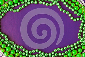 Mardi Gras or Fat Tuesday comp osition. Green mardi gras beads on purple background. Flat lay, copy space for text photo