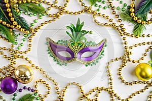 Mardi Gras mask, beads, and ornaments on white wood